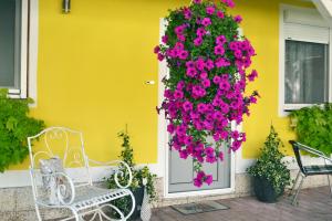 eine weiße Bank vor einem gelben Haus mit rosa Blumen in der Unterkunft Ferienwohnung Gerersdorf in Gerersdorf bei Güssing
