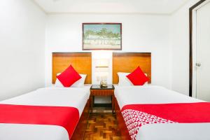 2 camas en una habitación de hotel con almohadas rojas en Super OYO 406 Royale Parc Inn & Suites, en Manila
