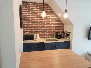 a kitchen with blue cabinets and a brick wall at Dépendance au goût de vacances in Moulainville-la-Basse