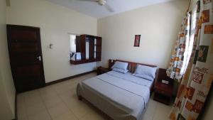 Schlafzimmer mit einem Bett, einem Fenster und einer Tür in der Unterkunft Marigold Guest House in Mombasa