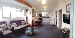 a living room with couches and a table and a kitchen at Haven on Haven in Moeraki