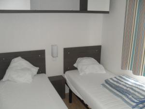 Duas camas num quarto com lençóis e almofadas brancos em Camping de la Mer em Camiers