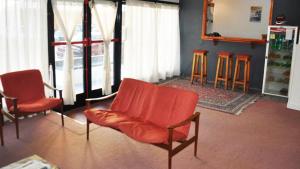 a living room with two orange chairs and bar stools at Hotel Carama in Necochea