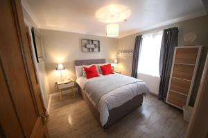 Schlafzimmer mit einem Bett mit roten Kissen und einem Fenster in der Unterkunft Number 4 in Exeter