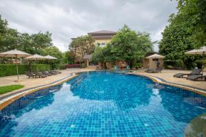 - une piscine avec des chaises longues et des parasols dans un complexe dans l'établissement Phufa Waree Chiangrai Resort - SHA Extra Plus, à Tha Sut