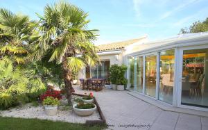a house with a patio with palm trees and plants at Locatlantique in Aytré