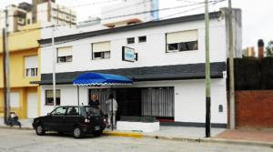 a car parked in front of a building with a blue umbrella at Hotel Carama in Necochea
