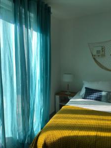 a bedroom with a bed and a window with blue drapes at Maxima Sunset in Sainte-Maxime