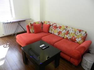 a living room with a red couch and a table at Chemi Saxli Apartment in Batumi