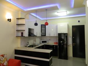 a kitchen with a black refrigerator and white cabinets at Chemi Saxli Apartment in Batumi