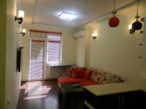 a living room with a red couch and a window at Chemi Saxli Apartment in Batumi