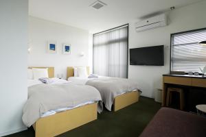 金沢市にあるsararasoのベッド2台とテレビが備わるホテルルームです。