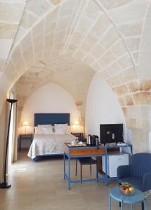 a bedroom with a bed and a desk with a television at Antica Masseria Torre Mozza in Torre Santa Susanna