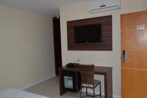 Una habitación con un escritorio y un televisor en la pared. en Sakr Hotel Rio Preto, en São José do Rio Preto