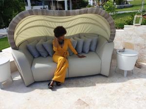 a woman sitting on a couch on a patio at casaenjoysamana in Los Naranjos