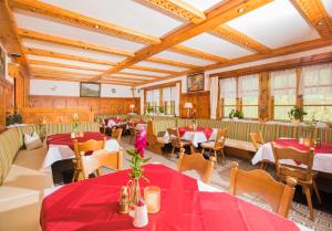 ein Restaurant mit roten Tischen, Stühlen und Fenstern in der Unterkunft Alpengasthof Praxmar in Sankt Sigmund im Sellrain