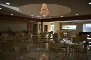 a restaurant with tables and chairs and a chandelier at Sakr Hotel Rio Preto in Sao Jose do Rio Preto