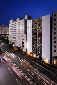 HOTEL FORZA HAKATAEKI CHIKUSHI-GUCHI Ⅰ في فوكوكا: مبنى كبير على شارع المدينة ليلا