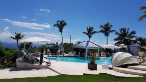 a resort swimming pool with a slide and palm trees at casaenjoysamana in Los Naranjos