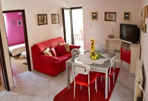 - un salon avec une table et un canapé rouge dans l'établissement Apartments Sunčica, à Mali Lošinj