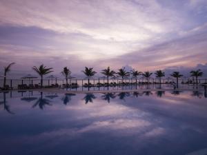 a pool of water with palm trees and a cloudy sky at Swandor Cam Ranh Resort-Ultra All Inclusive in Cam Ranh