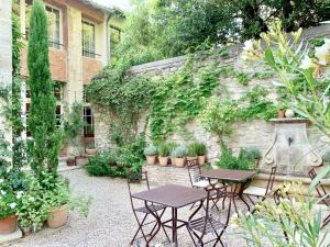 two tables and chairs in a garden next to a stone wall at Le Clos Saluces in Avignon