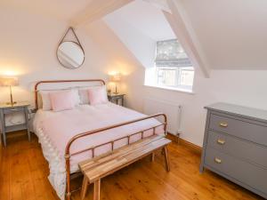 a bedroom with a bed with a bench and a mirror at Cherry Cottage in Whitby