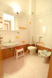 uma casa de banho com um lavatório, um WC e um lavatório. em Residenza Le Due Palme em Villasimius