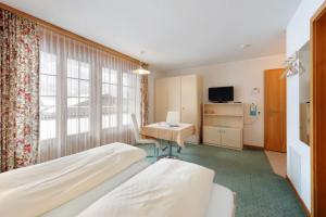 ein Hotelzimmer mit 2 Betten und einem Schreibtisch in der Unterkunft Apartments Kirchbühl in Grindelwald