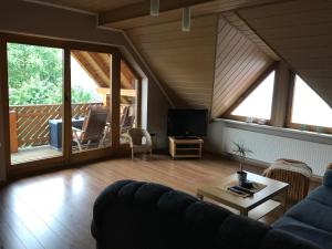 a living room with a couch and a tv and some windows at Fewo No. 17- Langgons / Oberkleen in Langgöns