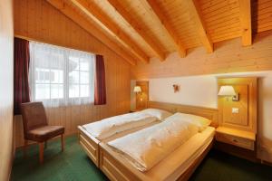 a bedroom with a large bed and a chair at Apartments Kirchbühl in Grindelwald