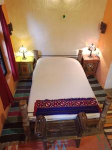 a large bed in a room with two tables and two lamps at The Mirage Andretta in Pālampur