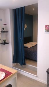 a bedroom with a bed and a blue curtain at Studio confort N2 Valenciennes Wifi Netflix in Aulnoy
