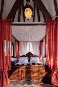 a bedroom with a large bed with red curtains at Naturresort Tannenhof GmbH in Großmaischeid