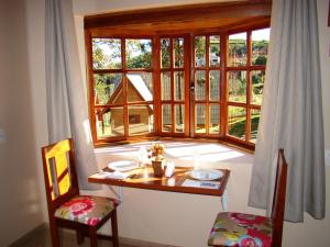 a table and two chairs in front of a window at Pousada Villa Di Carpi in Monte Sião