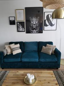 eine blaue Couch in einem Wohnzimmer mit Bildern an der Wand in der Unterkunft Le Petit Saint Ouennais à 30min de Paris in Saint-Ouen-lʼAumône