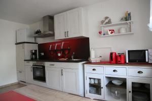 una cocina con armarios blancos y electrodomésticos rojos en Ferienwohnung Memmel, en Sulzfeld