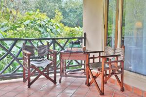 - une terrasse couverte avec 2 chaises, une table et un bureau dans l'établissement Jim's Jungle Retreat, à Rāmnagar