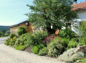 拉姆Woidhaisl的一座花园,花园内种有鲜花和一棵树,毗邻一座建筑