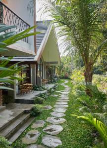 a pathway leading to a house with a palm tree at Yarama Cottages in Ubud