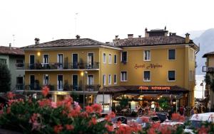 a large yellow building with cars parked in a parking lot at Hotel Alpino in Malcesine