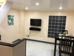 a living room with a table and a television on the wall at Rosetta Guest House in Ormoc +15 photos