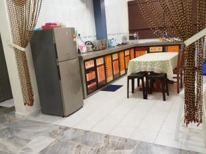 Il comprend une cuisine équipée d'un réfrigérateur et d'une table avec des chaises. dans l'établissement Aiman Homestay Port Dickson, à Port Dickson