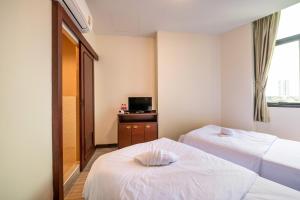 a hotel room with two beds and a television at Scala Hostel in Bangkok