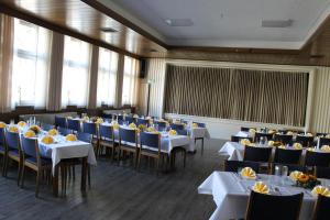 a banquet hall with tables and chairs with yellow flowers at Landhotel Schnier in Brilon