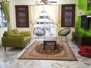 un salon avec un canapé vert et des chaises dans l'établissement Aiman Homestay Port Dickson, à Port Dickson