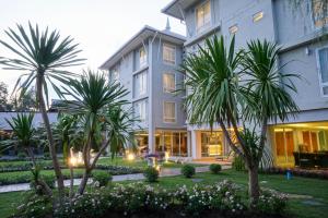 a hotel with palm trees in front of it at Nantra Chiangmai Riverfront Hotel in Chiang Mai