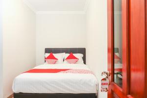 1 dormitorio con 1 cama con almohadas rojas y blancas en OYO 1519 Axl Residence, en Yakarta