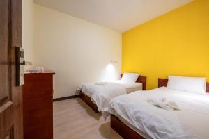 a bedroom with two beds and a yellow wall at Scala Hostel in Bangkok
