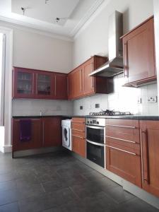 a kitchen with wooden cabinets and a stove top oven at WEST END - Stunning, spacious, 3 bedroom, main door flat with private parking in Glasgow